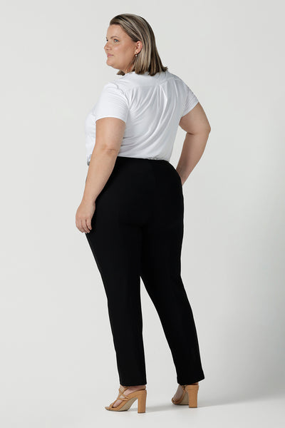 Back view of a plus size 18 woman wears slim leg, black pants by Australian and New Zealand women's clothing brand, L&F. These comfortable work pants are worn with a white Emily top in bamboo. Made in Australia for women size 8 - 24.