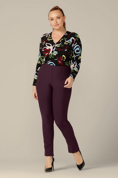 A size 12 woman wears slim leg pants in mulberry ponte jersey by Australia and New Zealand women's clothing brand, L&F. Good pants for work, they are worn with a long sleeve jersey top in black with an abstract print. 