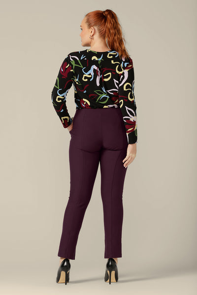 Back view of a size 12 woman wearing mid-rise, slim leg pants in mulberry ponte jersey with a long sleeve, printed jersey top, both by Australia and New Zealand women's clothing brand, L&F. Good pants for work, these comfortable trousers are made for an inclusive size range of 8 to 24.