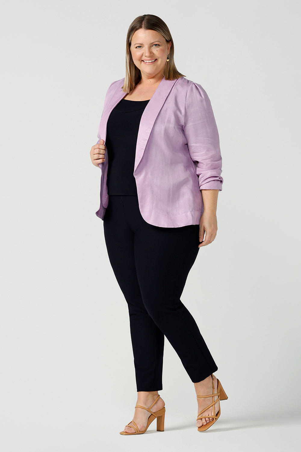 A size 18 curvy woman wears a linen blend blazer in lilac with a shawl collar. Soft tailoring details with shoulder tucks. Made in Australia size 8 - 24.