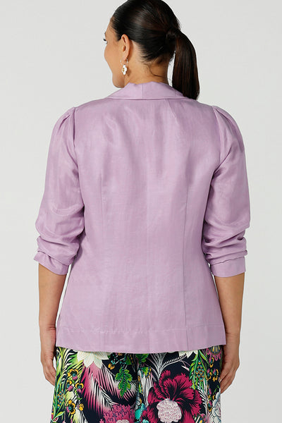 Back view of a size 12 curvy woman wearing a linen blend blazer in lilac with a shawl collar. Soft tailoring details with shoulder tucks. Made in Australia size 8 - 24.