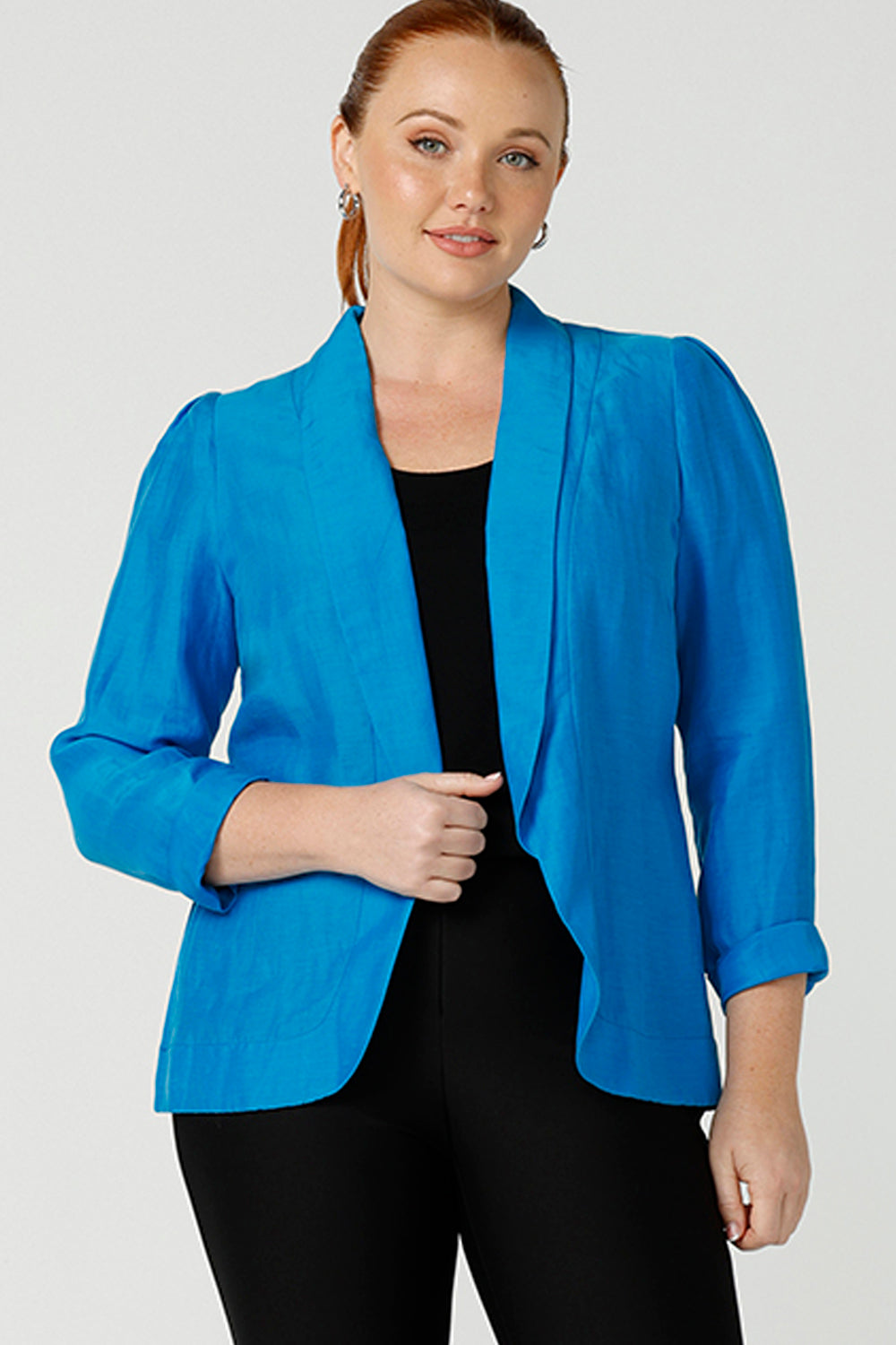 A curvy size, size 12 woman wearing a longline blazer in opal blue tencel fabric. This lightweight jacket is comfortable for your everyday workwear, casual and travel capsule wardrobe. Shop this Australian-made blazer online in sizes 8 to 24, petite to plus sizes.