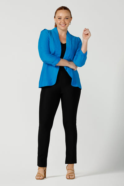 A curvy size, size 12 woman wearing a longline blazer in opal blue tencel fabric with black slim leg pants. This lightweight jacket is comfortable for your everyday workwear, casual and travel capsule wardrobe. Shop this Australian-made blazer online in sizes 8 to 24, petite to plus sizes.