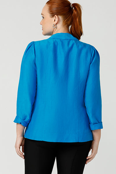 Back view of A curvy size, size 12 woman wearing a longline blazer in opal blue tencel fabric. This lightweight jacket is comfortable for your everyday workwear, casual and travel capsule wardrobe. Shop this Australian-made blazer online in sizes 8 to 24, petite to plus sizes.