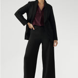 Full body back image of tall woman wearing. Black work wear pants. Easy care fabric used to craft pants is scuba crepe. Off duty pants provide breathable stretch and comfort. Australia Made for woman in Australia and New Zealand. Leina & Fleur is a woman’s clothing brand that has sizes ranging from 8 to 24 including short and regular lengths pants. 