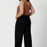 Full body back image of petite woman. wearing.black work wear pants. Easy care fabric used to craft pants is scuba crepe. Off duty pants provide breathable strech and ccomfort.  Australia Made for woman in Australia and New Zealand. Leina & Fleur is a woman’s clothing brand that has sizes ranging from 8 to 24 including plus sizes and petite sizes. 