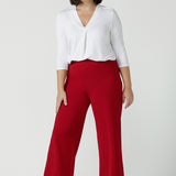 A size 10 woman wears the Drew pant in red, high waist and invisible fly front. Tailored belt loops and wide leg. Made in Australia for women. Stylish corporate wear for women. Made in Australia size 8 - 24.