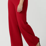 Close up of a size 10 woman wears the Drew pant in red, high waist and invisible fly front. Tailored belt loops and wide leg. Made in Australia for women. Stylish corporate wear for women. Made in Australia size 8 - 24.