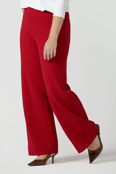Close up of a size 10 woman wears the Drew pant in red, high waist and invisible fly front. Tailored belt loops and wide leg. Made in Australia for women. Stylish corporate wear for women. Made in Australia size 8 - 24.