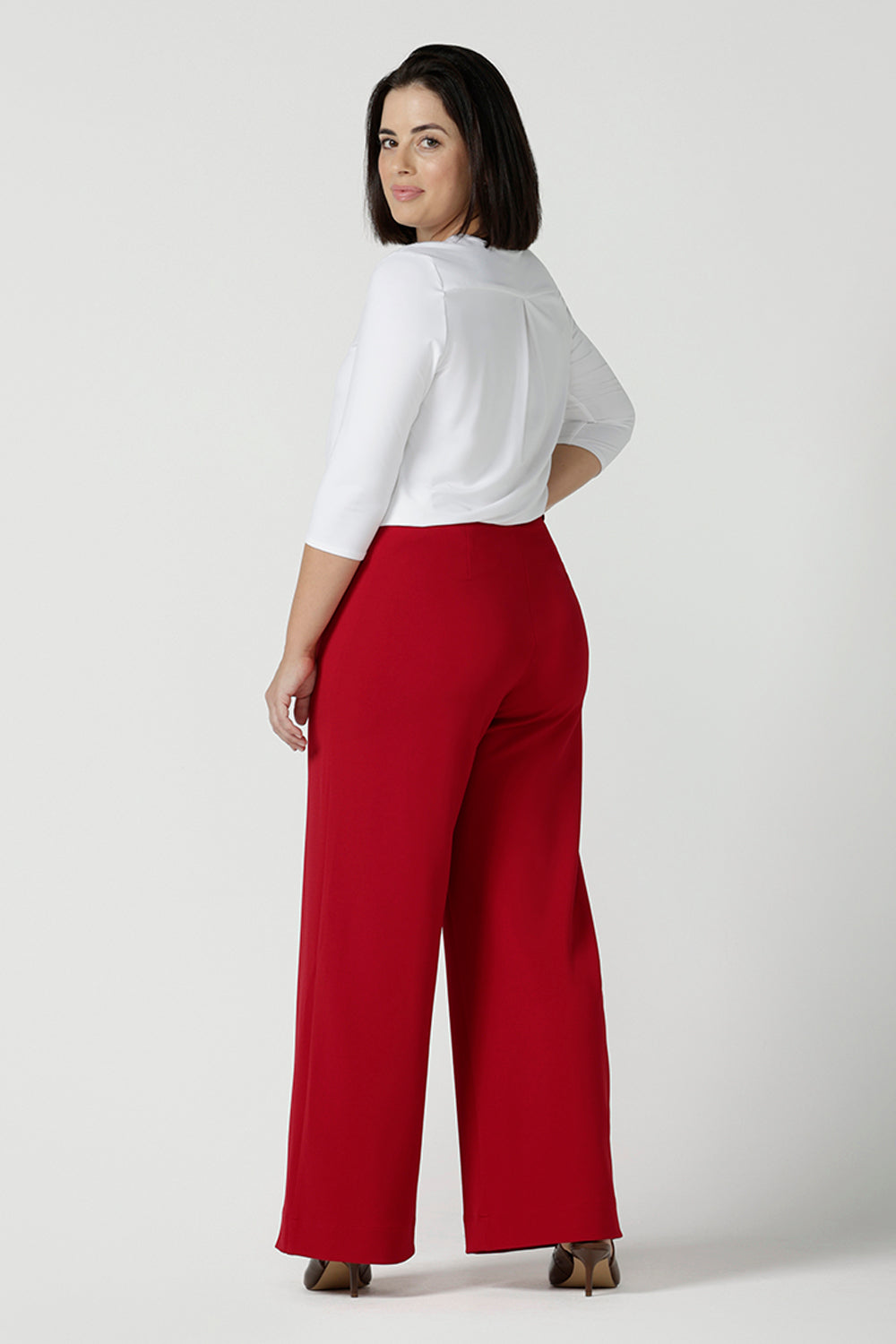 A size 10 woman wears the Drew pant in red, high waist and invisible fly front. Tailored belt loops and wide leg. Made in Australia for women. Stylish corporate wear for women. Made in Australia size 8 - 24.