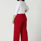 A size 10 woman wears the Drew pant in red, high waist and invisible fly front. Tailored belt loops and wide leg. Made in Australia for women. Stylish corporate wear for women. Made in Australia size 8 - 24.