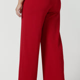 Back view of a size 10 woman wears the Drew pant in red, high waist and invisible fly front. Tailored belt loops and wide leg. Made in Australia for women. Stylish corporate wear for women. Made in Australia size 8 - 24.