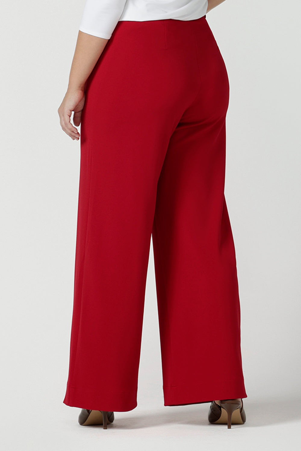 Back view of a size 10 woman wears the Drew pant in red, high waist and invisible fly front. Tailored belt loops and wide leg. Made in Australia for women. Stylish corporate wear for women. Made in Australia size 8 - 24.