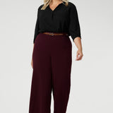 The high-rise design offers a flattering and comfortable fit, with a waistband that includes belt loops for added styling options. The invisible front zip with an internal button ensures a sleek, streamlined look while providing a secure fit. Size 18 model wears wide leg workwear pants with black blouse.