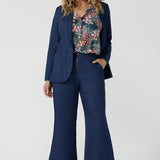 A size 10 woman wears the Bowie Top in jersey with flutter sleeves and tick neckline. Styled back with Denim Pants. Made in Australia for women size 8-24. Styled back with the Presley Pant in Whimsy. Styled with Denim Blazer and pant. 