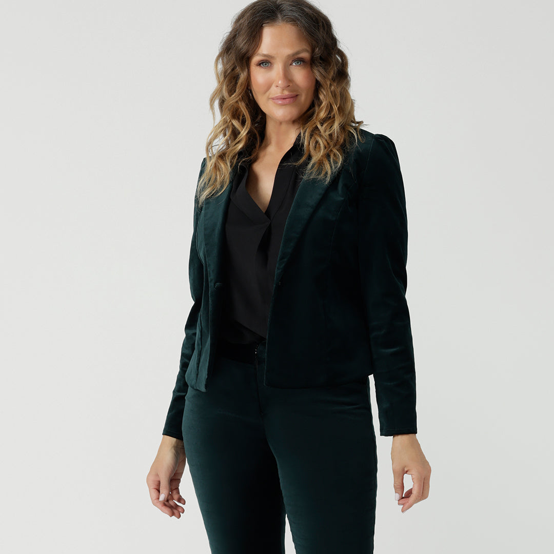 A size 12 woman wears a sustainable black dress shirt under a green velveteen cocktail pants suit for women. Shop this women's clothes online at Australian and New Zealand fashion brand, Leina & Fleur.