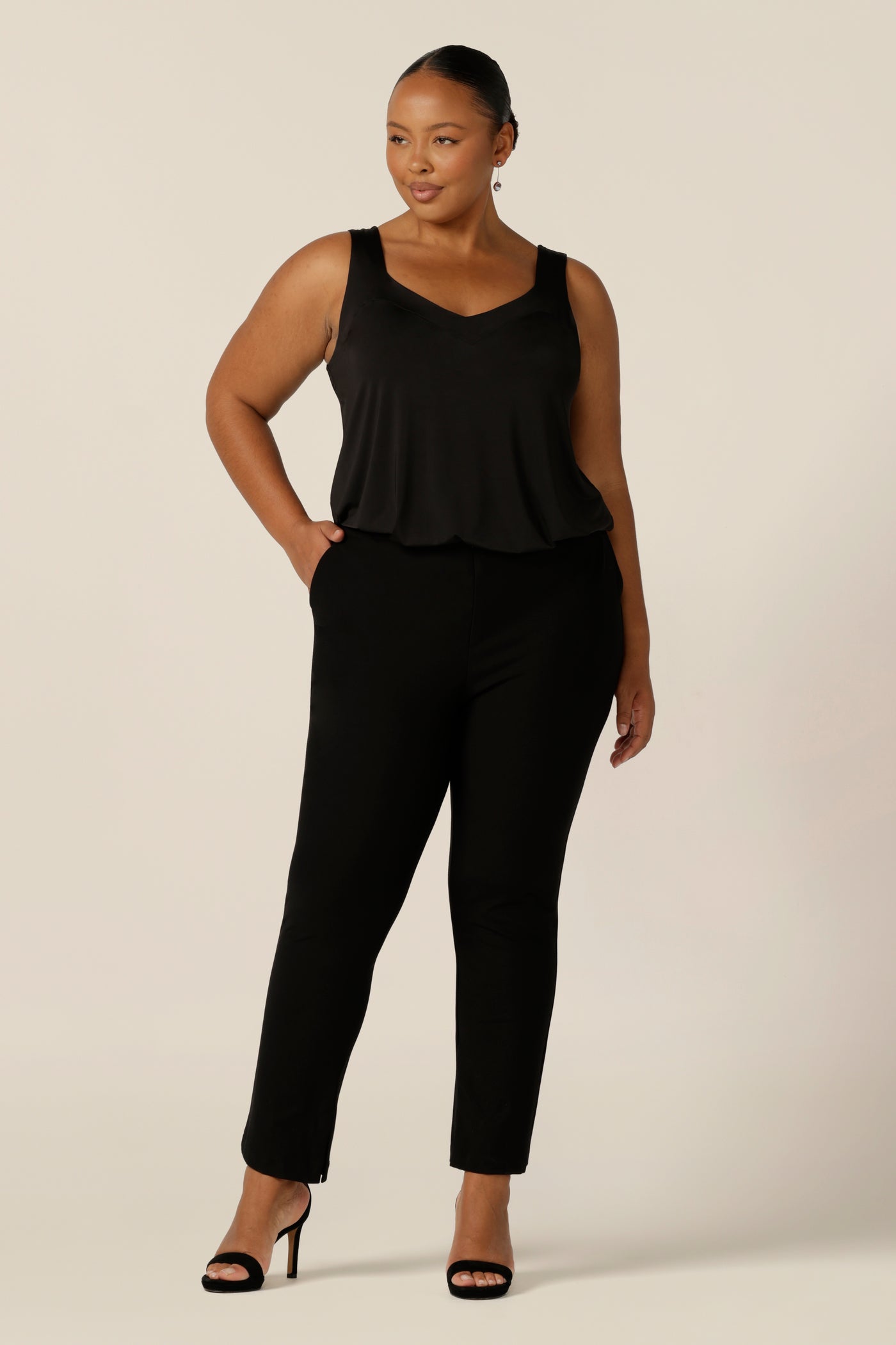 A size 18, fuller figure woman wears a black cami top with wide shoulder straps. Made in Australia by Australian and New Zealand women's clothing company, this slinky jersey top wears well with evening and occasionwear skirts, pants and suit jackets.