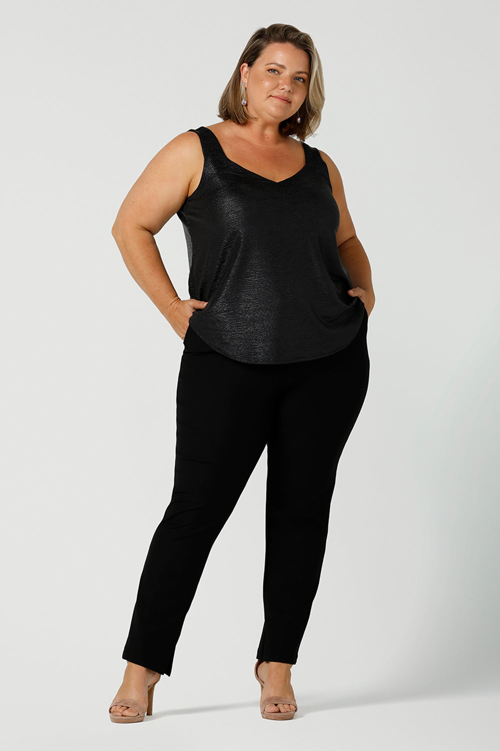  A size 18, fuller figure woman wears a black Xanadu cami top with wide shoulder straps. Made in Australia by Australian and New Zealand women's clothing company. She wears this shimmer jersey top with black pants for a classic evening look. 