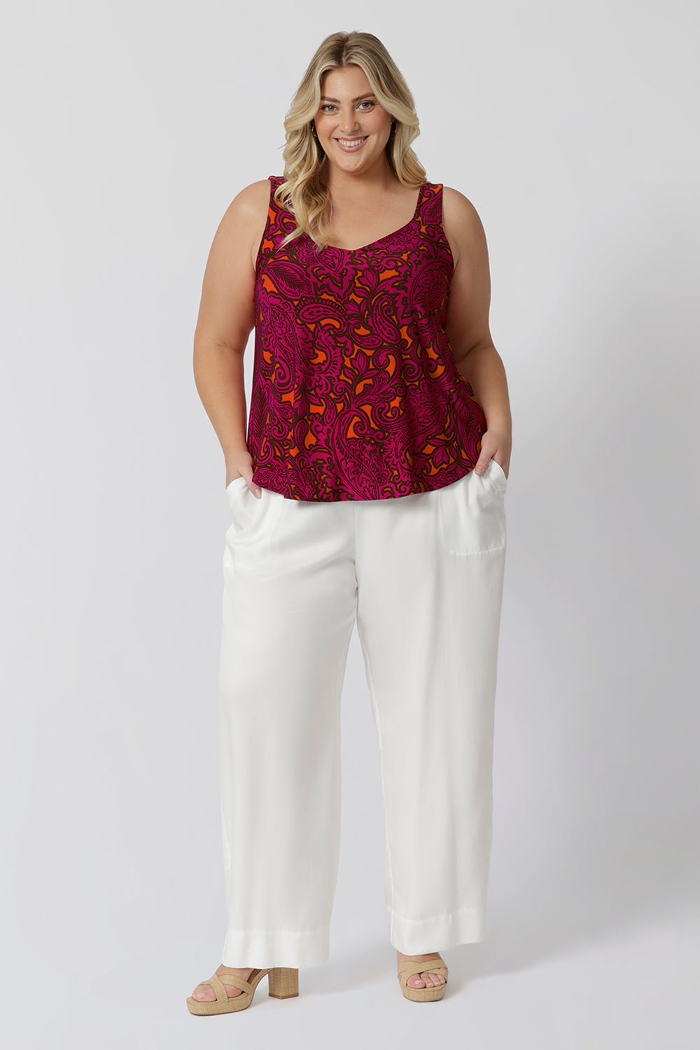 Plus sized woman wears fuchsia and tangerine paisley printed cami. This summer ready top is sleeveless and has a v neck design in both the front and back. Easy care fabric used to craft this cami is soft touch jersey fabric ensuring a comfortable and cool wear for all sizes 8-24.