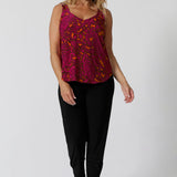 Front view of 40 year old woman wears v neck cami in a fuchsia and tangerine paisley print. Summer ready top is sleeveless and has been crafted with soft touch jersey fabric ensuring a comfortable and cool wear.