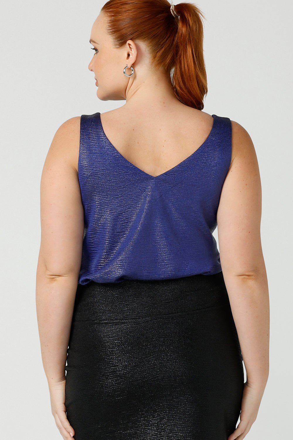 Back view of a size 12, fuller figure woman wearing a cobalt Xanadu cami top with wide shoulder straps. Made in Australia by Australian and New Zealand women's clothing company, this shimmer jersey top wears well with evening and occasion-wear skirts, pants and suit jackets.