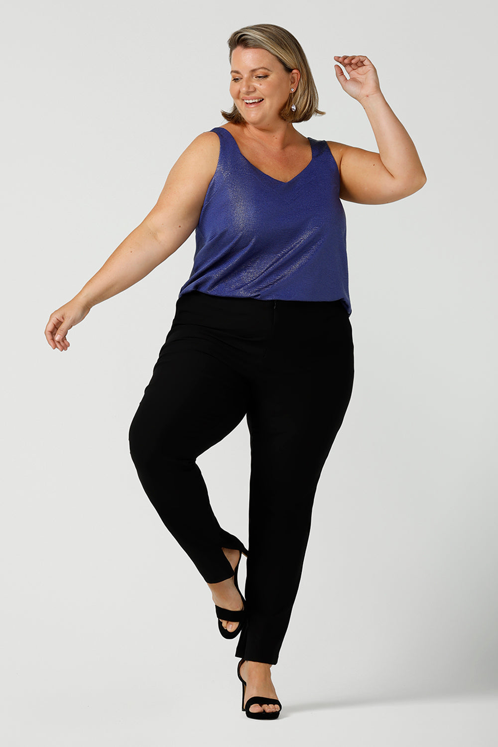 A size 18, fuller figure woman wears a cobalt Xanadu cami top with wide shoulder straps. Made in Australia by Australian and New Zealand women's clothing company. She wears this shimmer jersey top with black pants for a classic evening look. 
