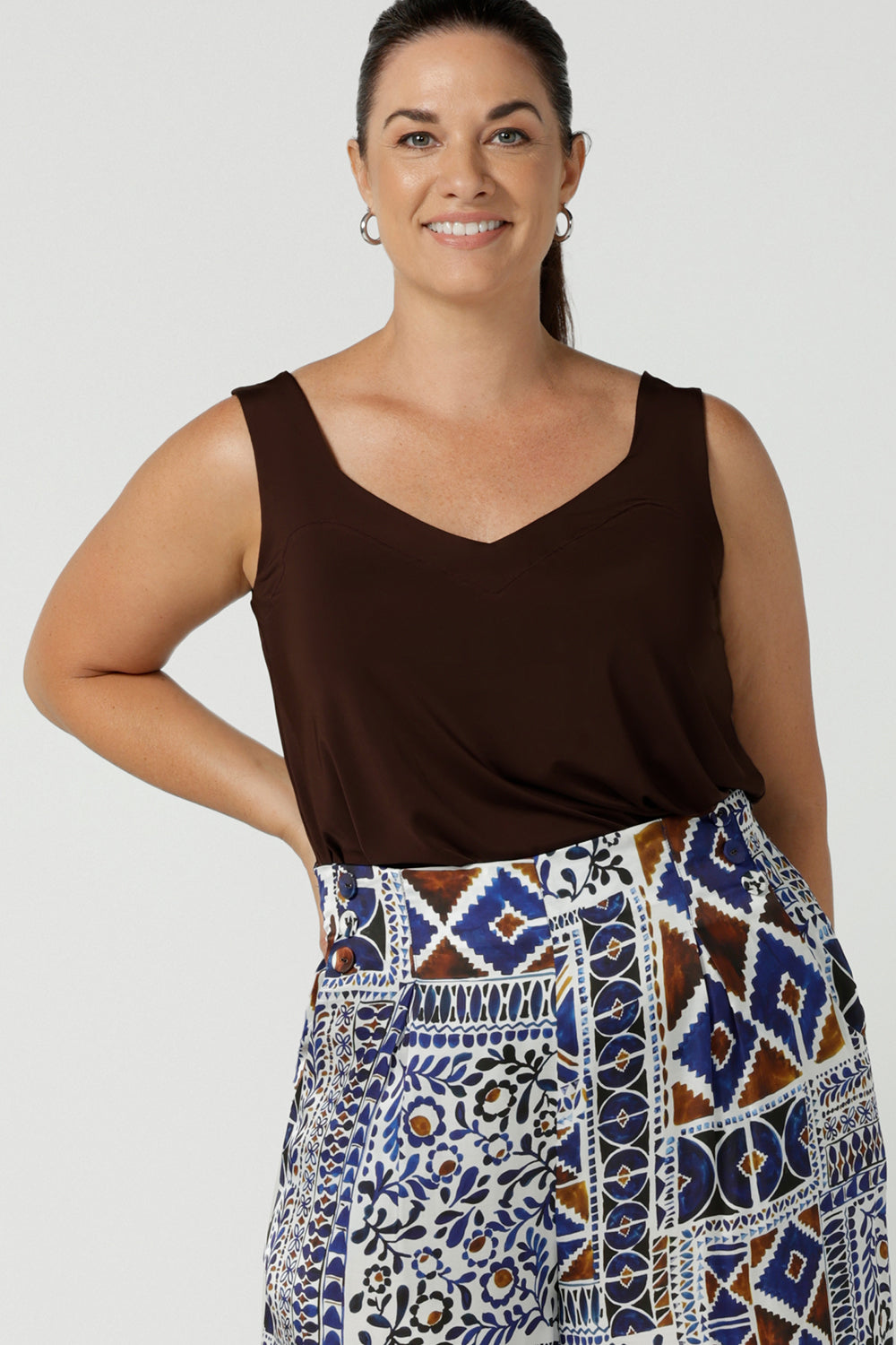 A size 12 woman wears the Eddy Cami in Cocoa a soft jersey cami style with wide straps for bra coverage. A comfortable work to weekend piece and great for layering back with a blazer. Styled back with the Ellery pants in Italian Viscose. Made in Australia for women size 8 to 24.