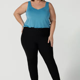 Size 18 Curvy woman wears the Brooklyn pant in black. It has a slim leg and functional pockets with invisible fly front detail. Styled back with an Eddy cami in Mineral.  Made in Australia for women size 8 - 24.