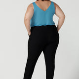 Back view of a size 18 curvy woman wears the Brooklyn pant in black. It has a slim leg and functional pockets with invisible fly front detail. Styled back with an Eddy cami in Mineral. Made in Australia for women size 8 - 24.