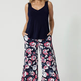 Full body shot of 40 year old woman wearing floral long pants. Made from easy care dry touch jersey fabric. Printed design has a combination of white and pink roses on navy pant base. These pants are comfortable, breathable and easy for travel. Designed in Australia by Australian and New Zealand women. Leina and Fleur is a fashion brand for woman that have sizes from 8 to 24. Shop this look now.