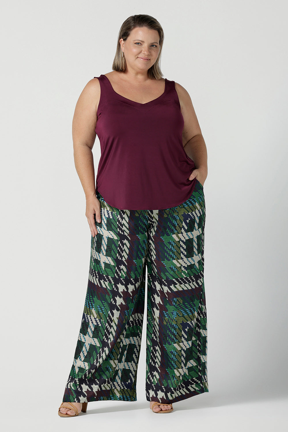 Size 18 woman wears the Eddy Cami top in Plum with wide straps. Made in Australia for women size 8 -24. style back with high waist Lulu pants in Navy. Soft tailored pants.