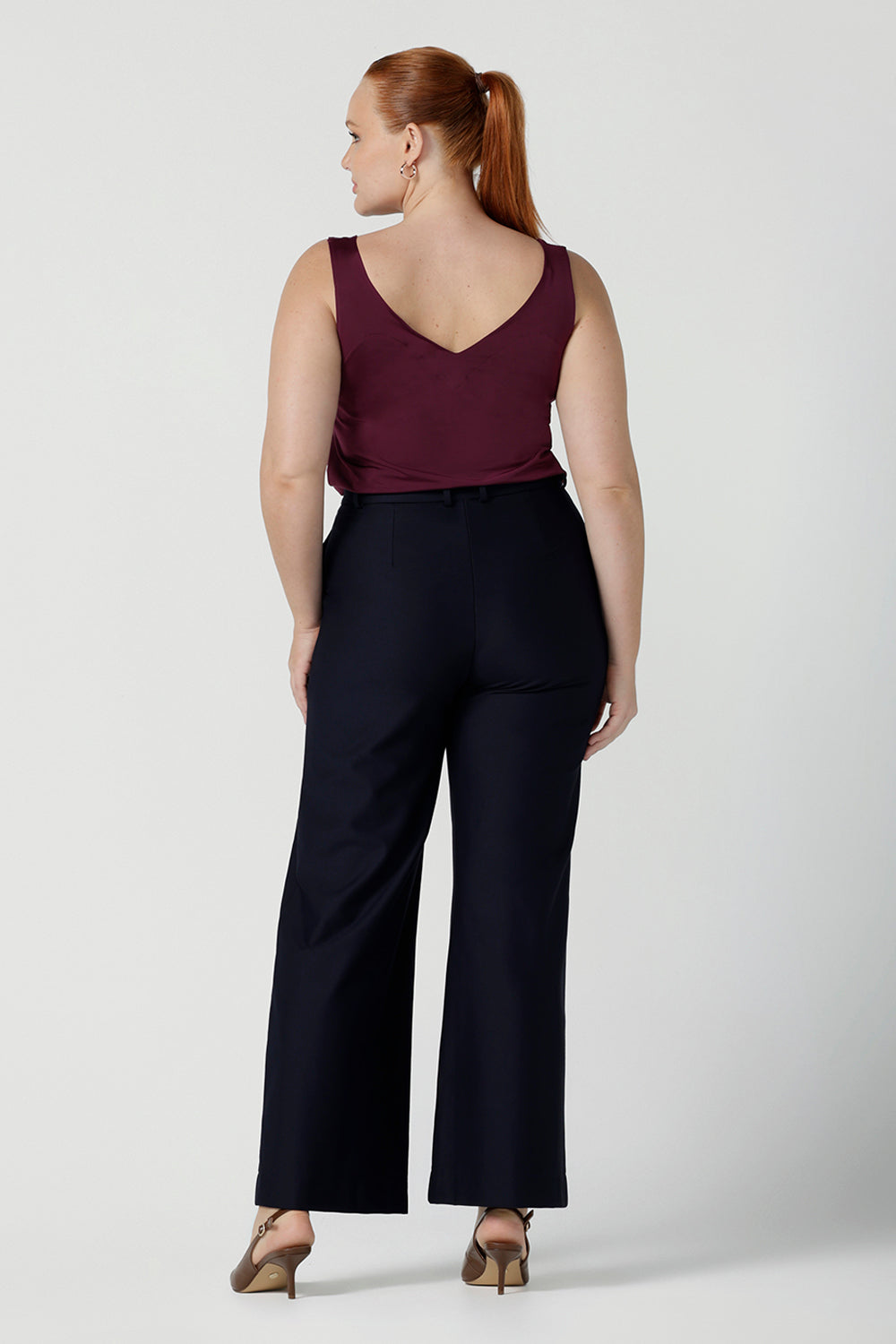 Size 12 woman wears the Eddy Cami top in Plum with wide straps. Made in Australia for women size 8 -24. style back with high waist Lulu pants in Navy. Soft tailored pants.