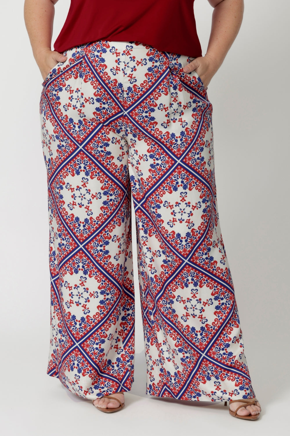 The pants are designed with a flattering high waist that elongates the legs, and they flow effortlessly into wide-leg pant, making them both relaxed and sophisticated. The geometric print, detailed in blue and red, adds a bold, graphic element to the design, with sharp lines and subtle curves that create visual interest. 