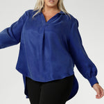 Plus size woman wears oversized blouse made from suede touch Tencel fabric. Workwear shirt features a collared V-neckline, cuffed sleeves and shirttail hemline that sits longer at the back. Woman's workwear clothing proudly made in Australia in sizes 8-24.