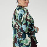 A sophisticated collared V-neckline with tailored centre tuck adds structure, while the full-length cuffed sleeves with covered buttons bring a polished finish. Long shirt tail hem for dramatic movement. Available in sizes 8-24.