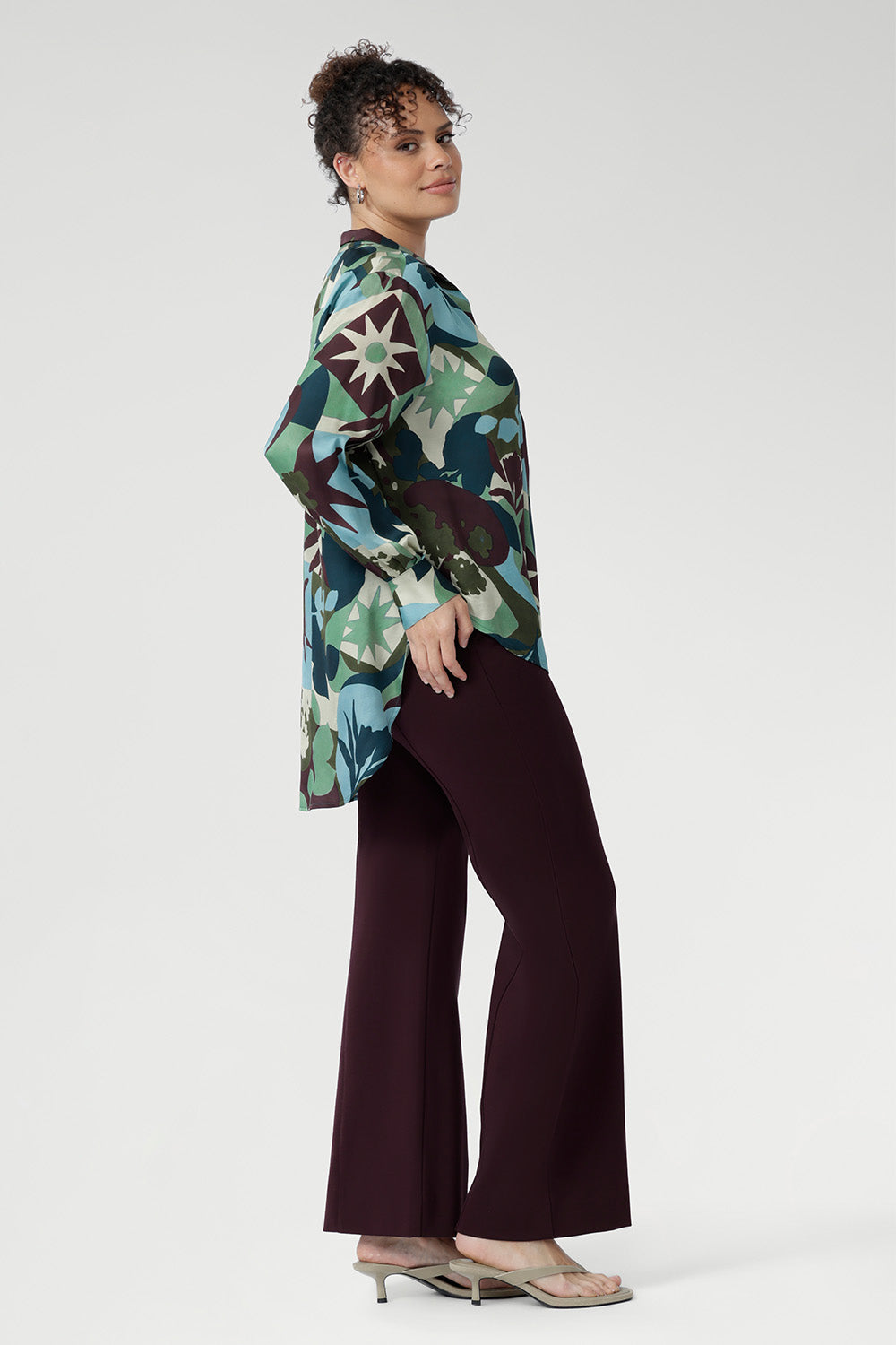 Designed with a flattering oversized silhouette, this effortless pull-on shirt drapes beautifully whether worn loose or stylishly front-tucked. The bold abstract print blends rich tones of green, blue, and plum, making it a standout for both professional and social settings.