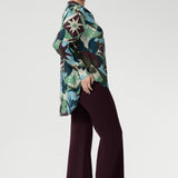 Designed with a flattering oversized silhouette, this effortless pull-on shirt drapes beautifully whether worn loose or stylishly front-tucked. The bold abstract print blends rich tones of green, blue, and plum, making it a standout for both professional and social settings.