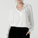 A size 10 woman wears the Ellis shirt in Vanilla tencel, a high quality made in Australia womens shirt made in breathable tencel. Inclusive size range 8-24 and made in Australia. Styled back with the Deni pants in Black velour.