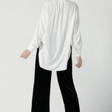 Back view of a size 10 woman wears the Ellis shirt in Vanilla tencel, a high quality made in Australia womens shirt made in breathable tencel. Inclusive size range 8-24 and made in Australia. Styled back with the Deni pants in Black velour.