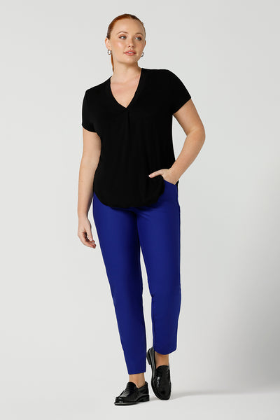 A good top for your capsule wardrobe, this V-neck black bamboo jersey top with short sleeves makes for a good office wear top for women, as well as a comfortable casual top. Worn with cobalt blue tailored pants and shown on a size 12 woman, this top is made for curvy women by Australian ladies clothing brand, Leina & Fleur. Shop black tops for women in sizes 8 to 24 in their online fashion boutique.