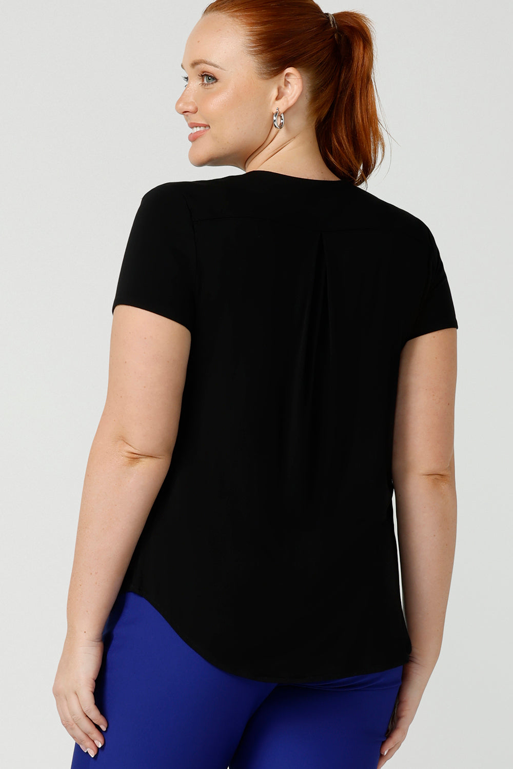 Back view of a good top for your capsule wardrobe. This V-neck bamboo jersey top with short sleeves makes for a good office wear top for women, as well as a comfortable casual top. Shown on a size 12 woman, this black jersey top is made for curvy women by Australian women's clothing brand, Leina & Fleur. Shop black tops for women in sizes 8 to 24 in their online fashion boutique.