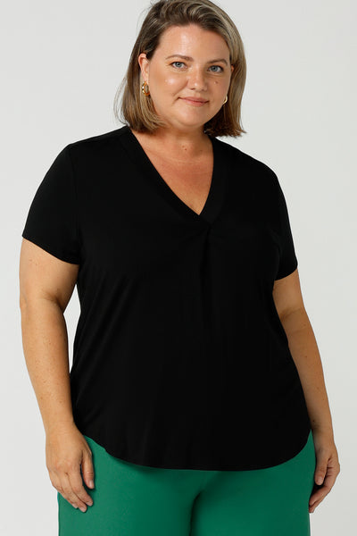 A good top for your capsule wardrobe, this V-neck black bamboo jersey top with short sleeves makes for a good office wear top for women, as well as a comfortable casual top. Shown on a size 18, curvy woman, this is a good top for plus size women. Made by Australian women's clothing brand, Leina & Fleur, shop black tops for women in sizes 8 to 24 in their online fashion boutique.