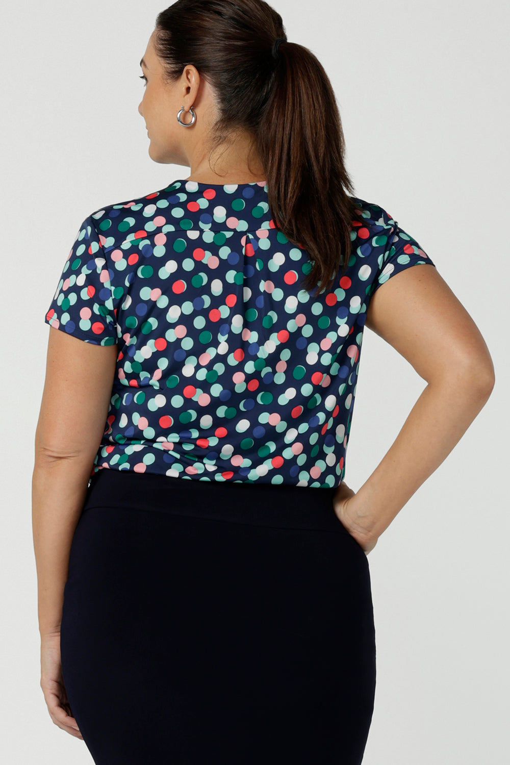 Back view of a happy corporate woman wearing the Emily Top in Blue bubbles spot print. Short sleeves with a pleat front. V-neckline and back yoke. Comfortable jersey fabric. Made in Australia for women size 8 - 24.