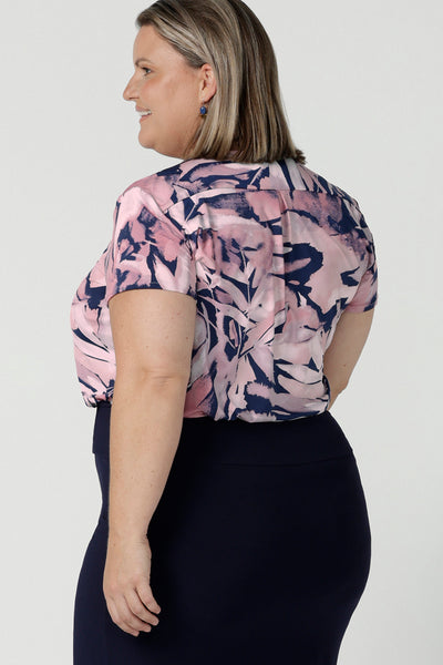 Back view of a size 18 woman wears a Emily top in Cantata with a navy base and pink brush strokes. V-neckline on a soft slinky jersey. Corporate casual top for women. Size 8 - 24
