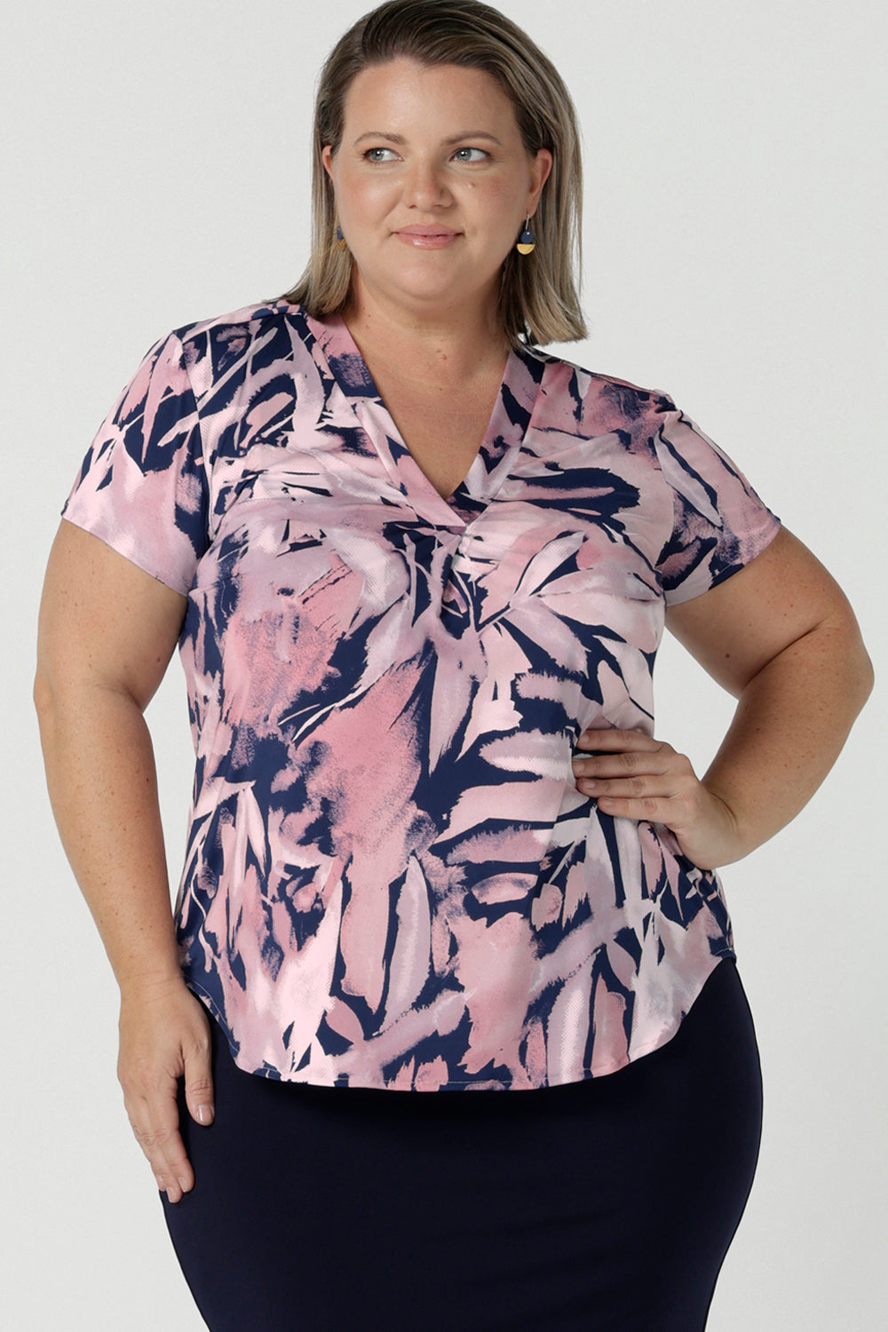 Size 18 woman wears a Emily top in Cantata with a navy base and pink brush strokes. V-neckline on a soft slinky jersey. Corporate casual top for women. Size 8 - 24