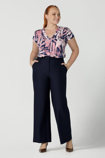 Size 12 woman wears a Emily top in Cantata with a navy base and pink brush strokes. V-neckline on a soft slinky jersey. Corporate casual top for women. Size 8 - 24.