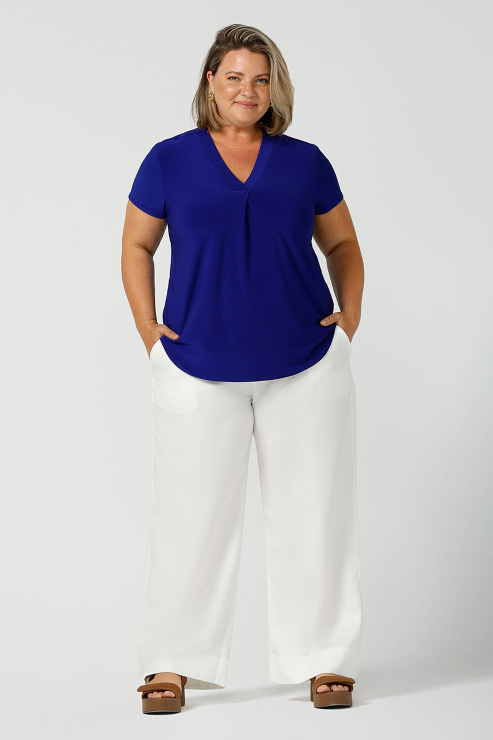 a size 18 woman wears a v-neck  jersey top in cobalt blue. She wears the top with white wide leg pants for summer. Designed and made in Australia for petite to plus size women.