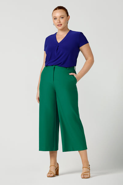a curvy size 12 woman wears a v-neck  jersey top in cobalt blue. She wears the top with emerald green tailored wide leg pants for work or casual. Designed and made in Australia for petite to plus size women.