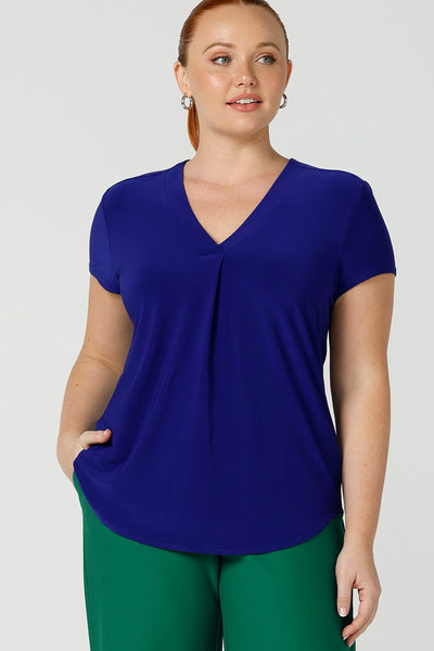 a curvy size 12 woman wears a v-neck  jersey top in cobalt blue. She wears the top with emerald green tailored wide leg pants for work or casual. Designed and made in Australia for petite to plus size women.