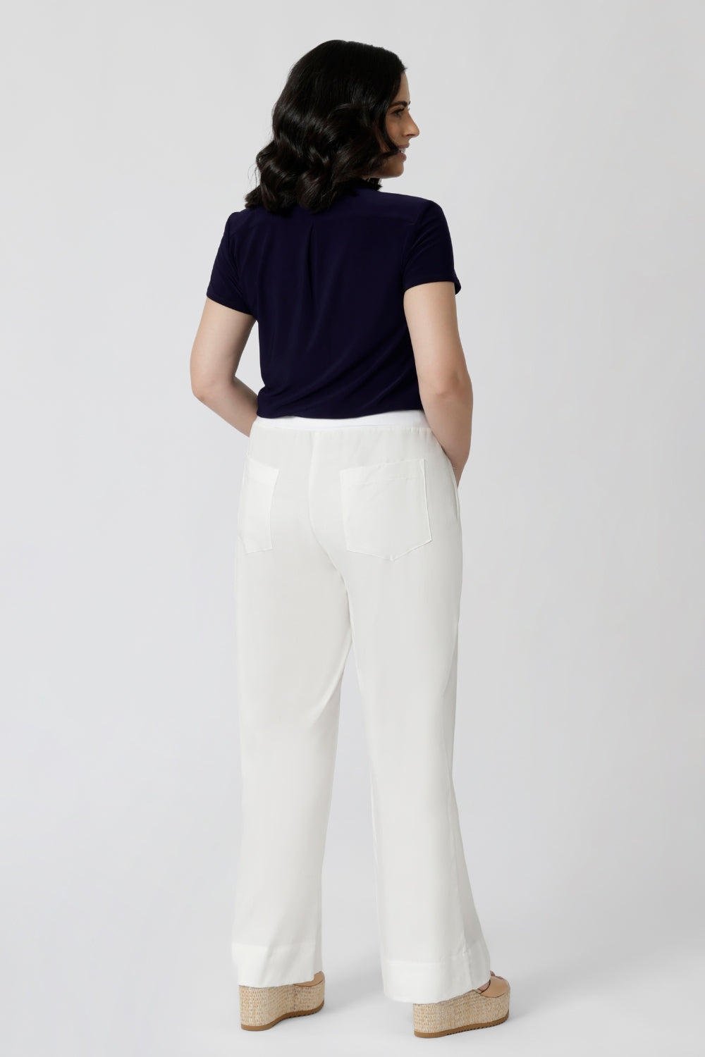 back view of a navy summer top worn with white pants